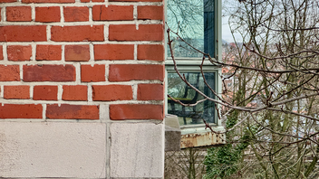A brick building with a chair reflected in the window of another building.