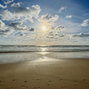 A pair of footprints are in the sand along the shoreline.